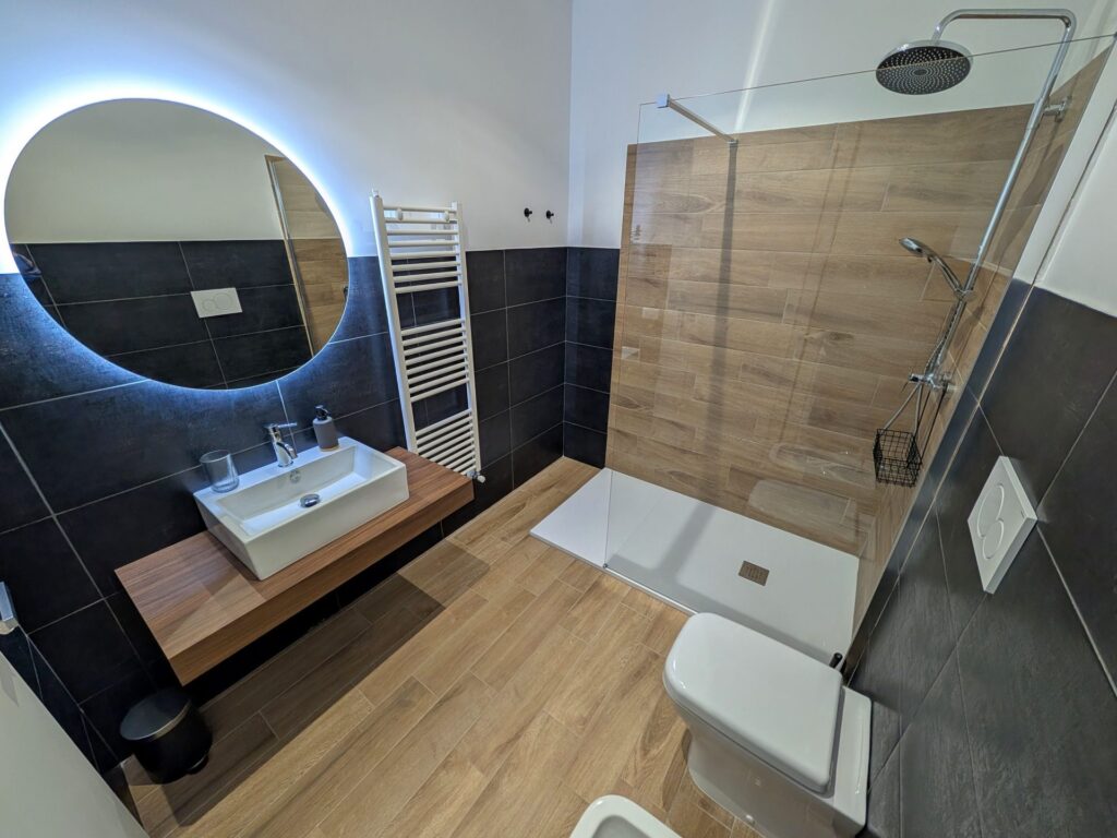 Bagno privato con doccia walk-in, specchio LED e lavabo su mensola in legno, Camera Porta San Martino, B&B a Lecce