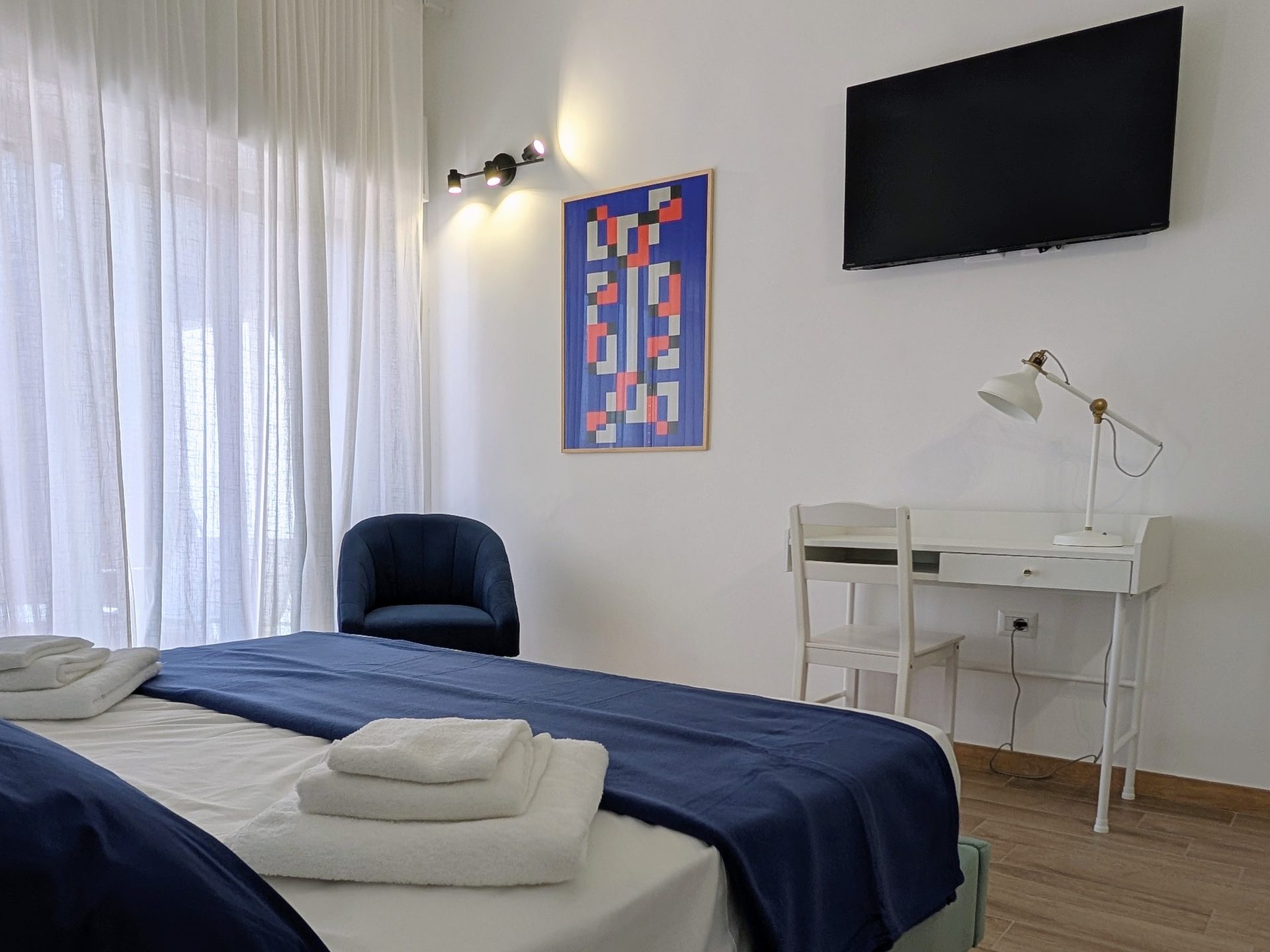 Camera con scrivania, poltroncina blu e smart TV a parete in B&B a Lecce