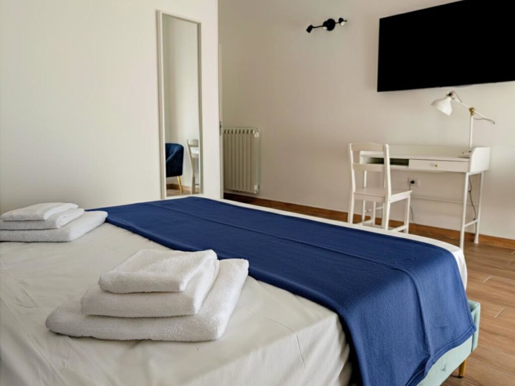 Set di asciugamani sul letto con scrivania e specchio sullo sfondo, Camera Porta Napoli, B&B a Lecce