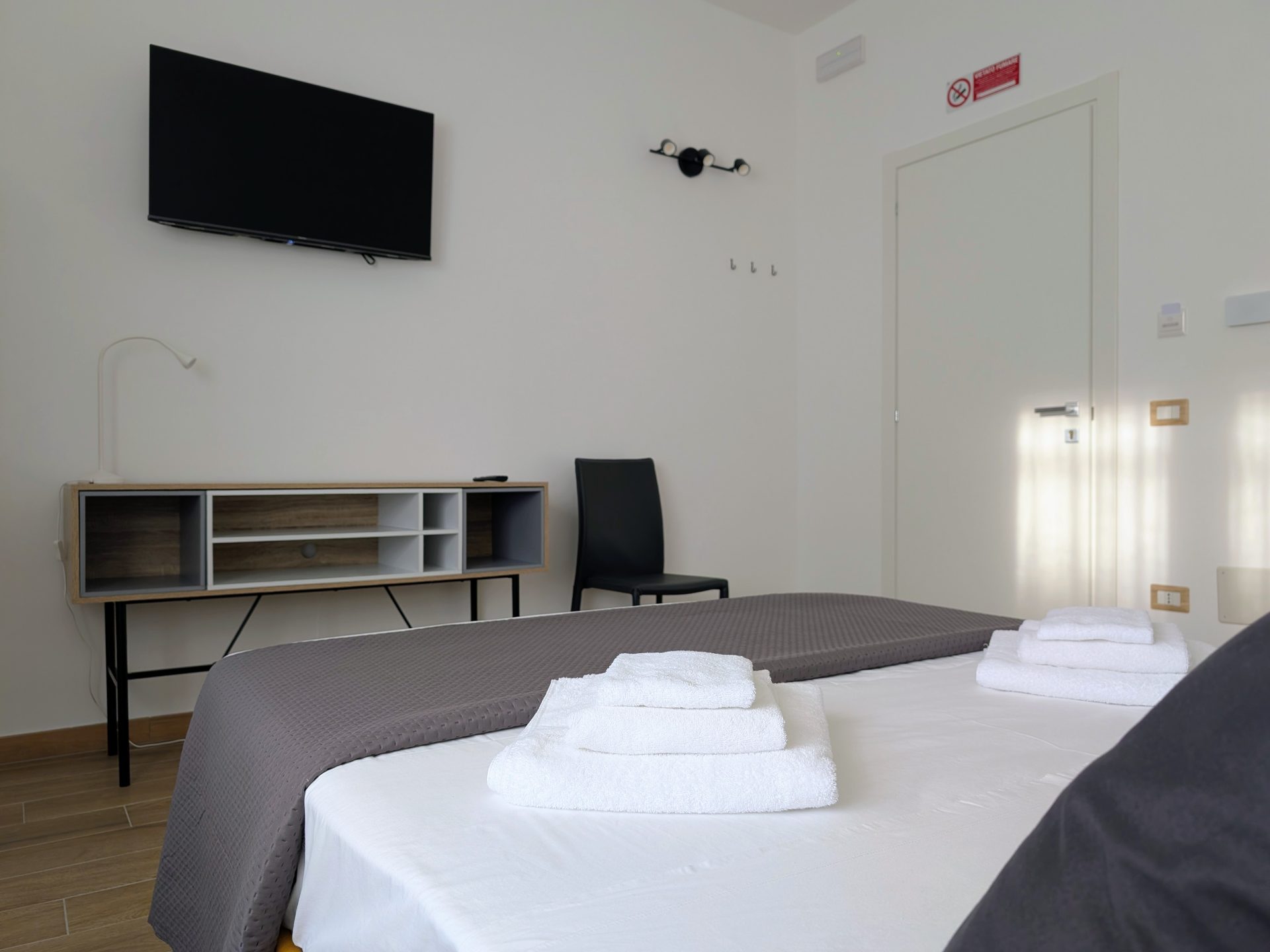 Set di asciugamani sul letto con scrivania e Smart TV sullo sfondo, Camera Porta San Martino, B&B a Lecce
