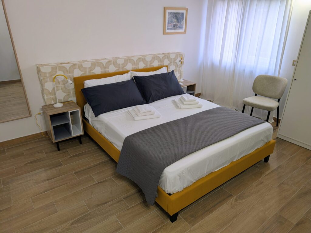 Letto matrimoniale con testiera ocra e boiserie decorata nella Camera Porta San Martino, B&B a Lecce